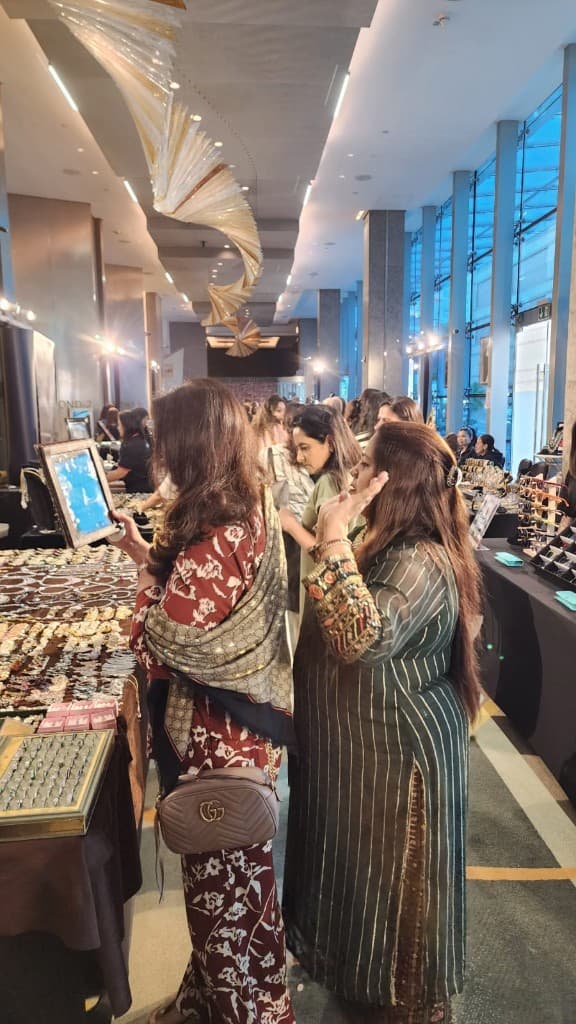Sopritti exhibition — guests browsing jewellery along a bright corridor with floor-to-ceiling windows