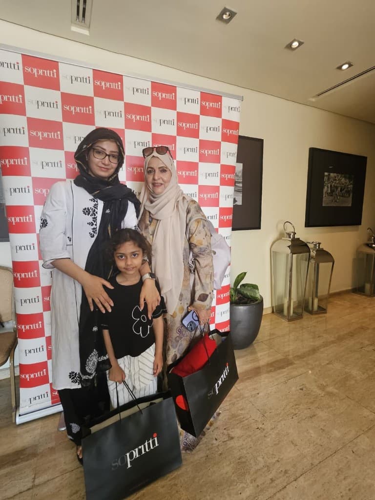 Family posing with Sopritti shopping bags at the red and white checkered exhibition backdrop