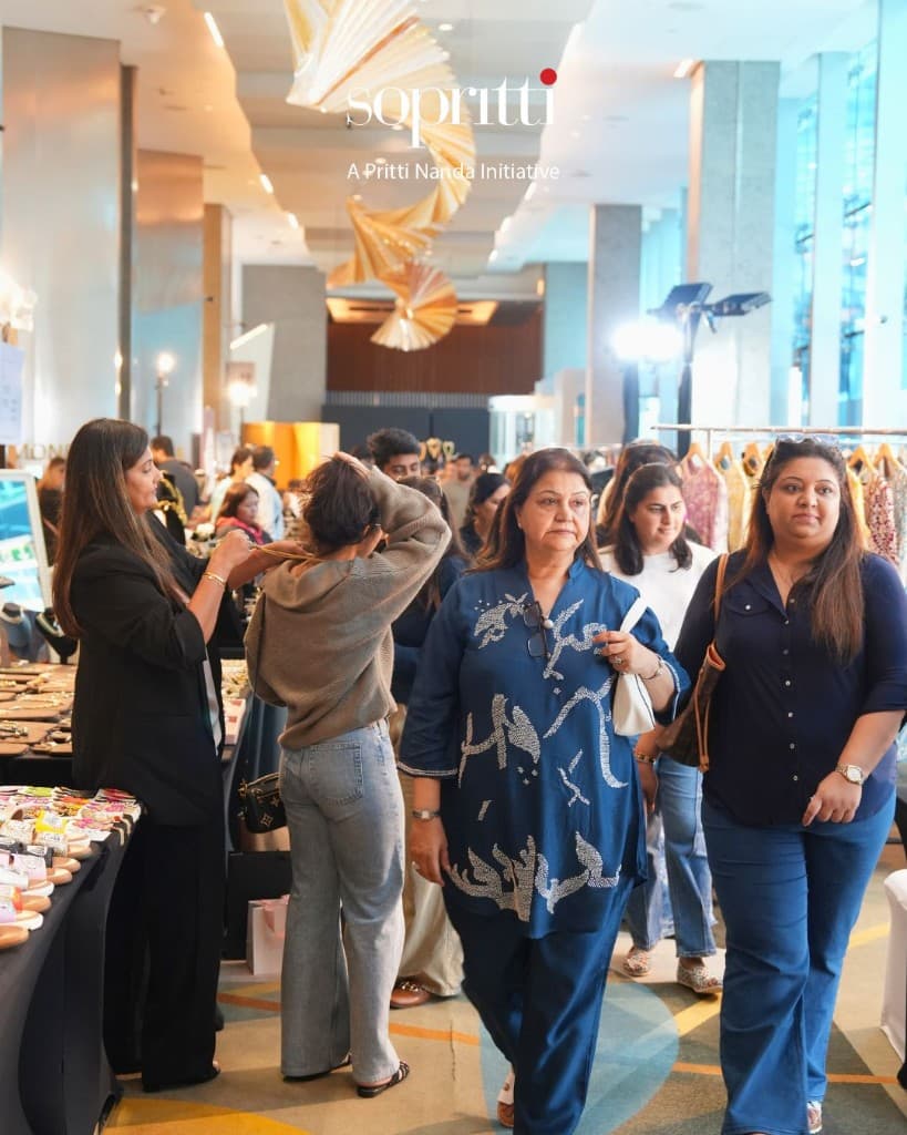 Guests browsing gold and pearl jewellery at a crowded Sopritti exhibition table